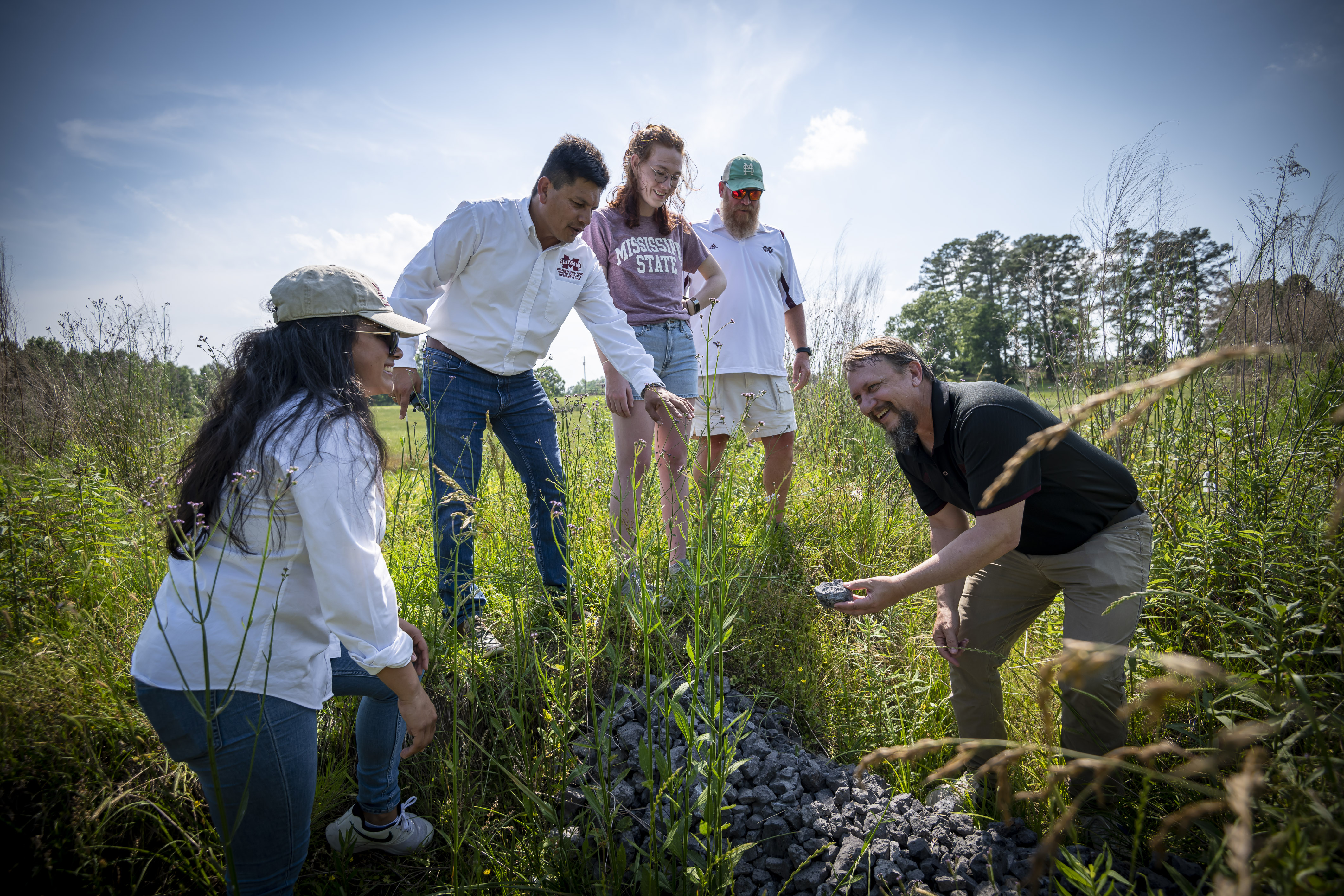 Dr. Tim Schauwecker (right), and Dr. John Ramirez-Avila, show a piece of slag to students in the field. (Photo by David Ammon)